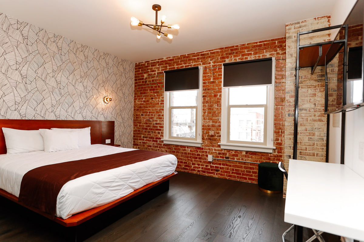 A hotel room with a bed, desk, and windows