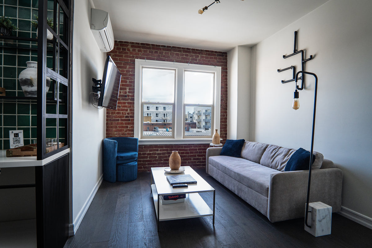 A modern living room with a gray sofa, coffee table, and brick wall.