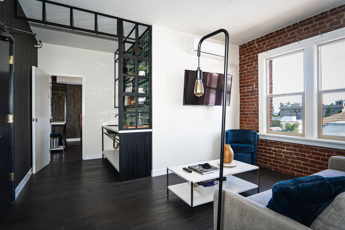 A modern living room with a brick accent wall, industrial-style decor, and a view of the city through the window.